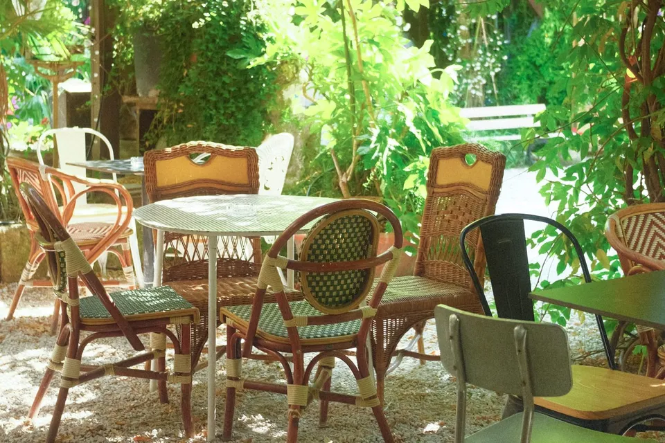 Een terras met tuinstoelen onder een houten overkapping