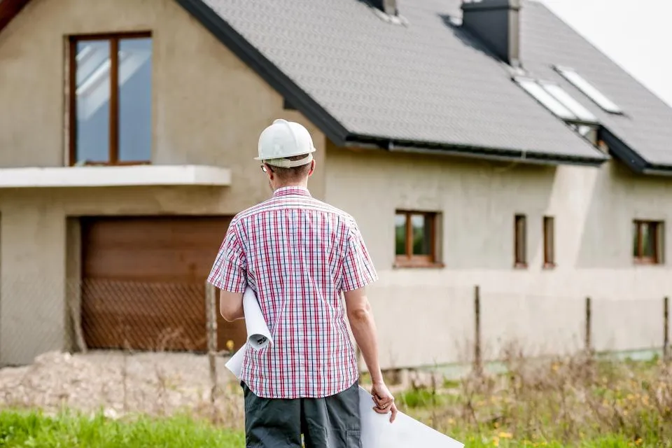 Een uitvoerder met een bouwtekening bij een nieuwbouwwoning